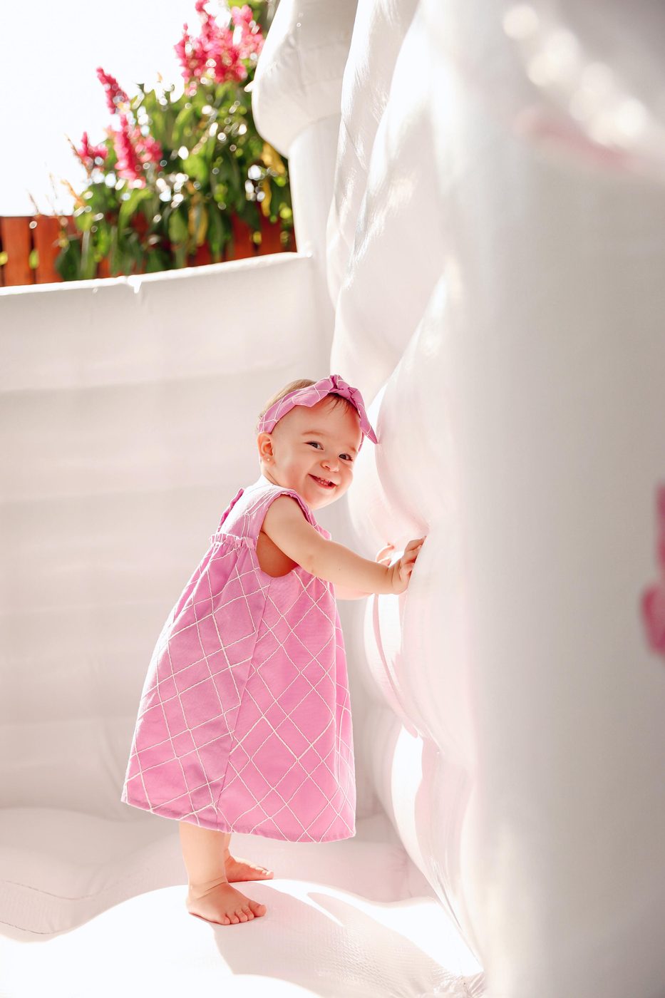 Bebê de vestido rosa brincando dentro do castelo branco