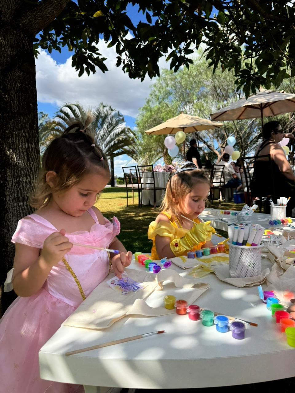 Meninas vestidas de princesa pintando ecobags no jardim